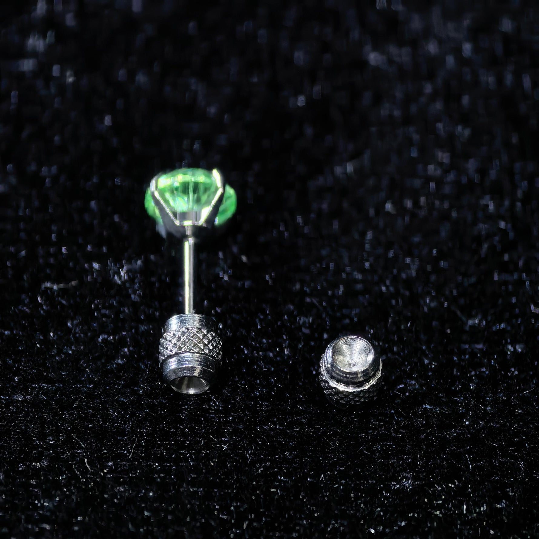 Close‑up shot of green cubic zirconia cartilage piercing stud earring, knurled textured easy‑grip threaded screw‑back titanium steel ear jewellery for ear stacking